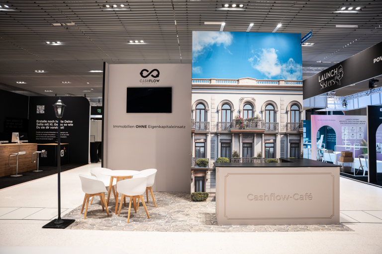 Moderner Messestand für Immobilien mit Café-Konzept und großflächigem Gebäudedesign